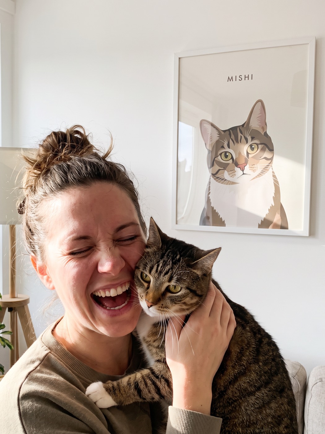 Una clienta abrazando a su gata junto al retrato colgado en el salón